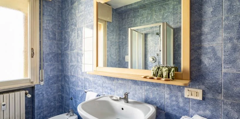 Un baño con azulejos azules, lavabo y espejo.