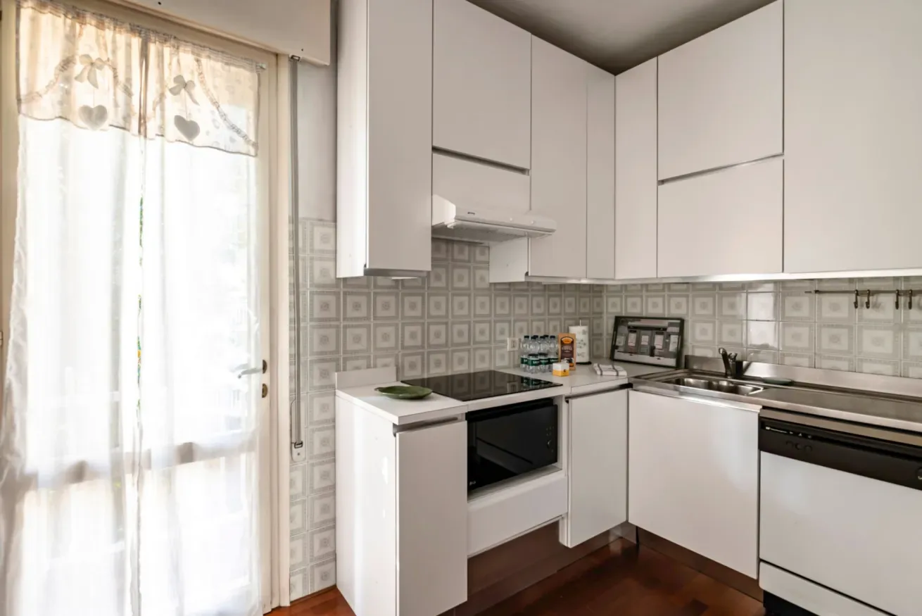 Una cocina luminosa con armarios blancos y un salpicadero estampado.