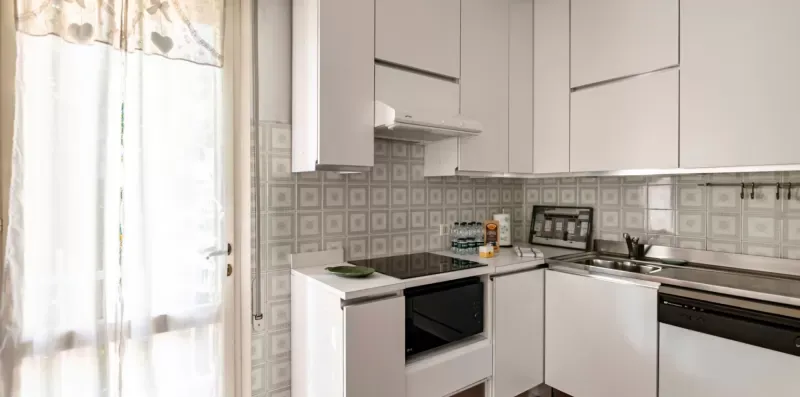 Una cocina luminosa con muebles blancos y un salpicadero estampado.