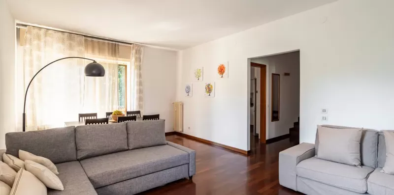 Una sala de estar con asientos grises, una lámpara de pie curva y arte en la pared.