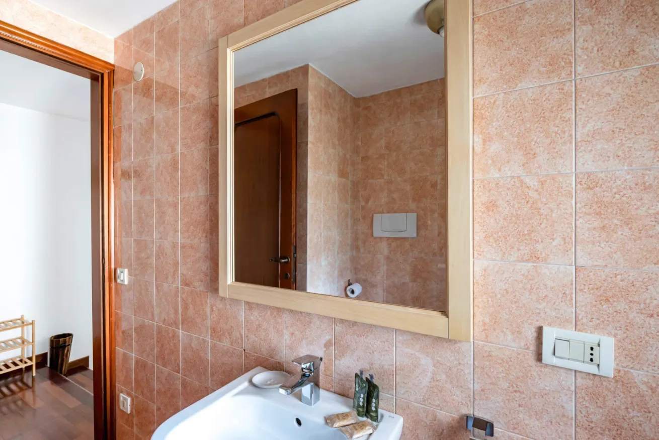 Un baño con azulejos, un lavabo y un espejo grande en la pared.