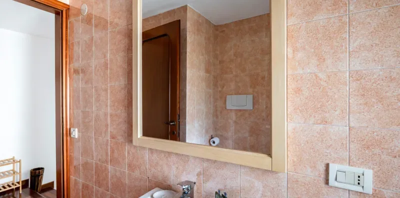 Un baño con azulejos, un espejo de pared y un lavabo.