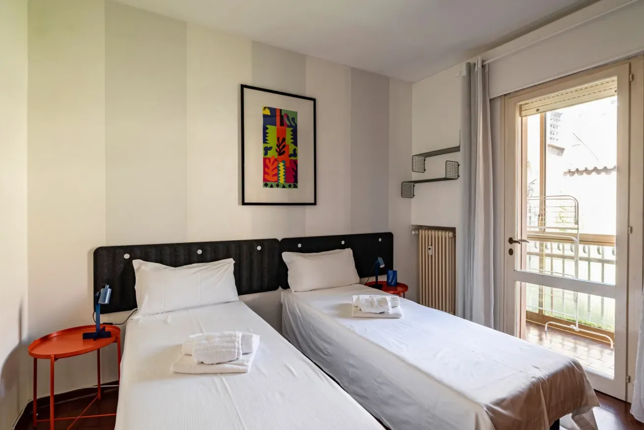 Un dormitorio con dos camas y una puerta de vidrio que da a un balcón.