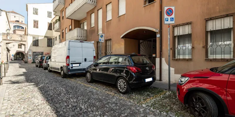 Una calle adoquinada bordeada de coches estacionados y edificios de apartamentos.