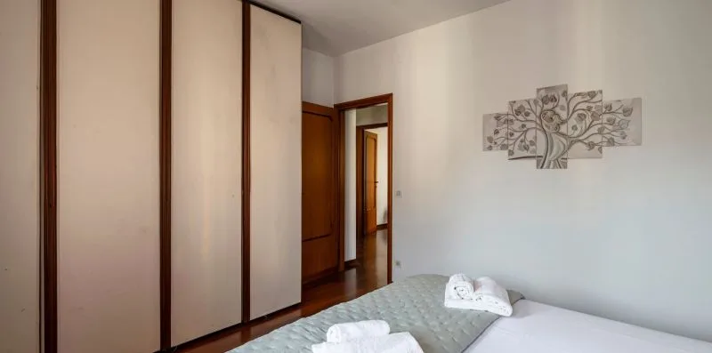 Un dormitorio con una cama, armarios empotrados y un cuadro de un árbol.