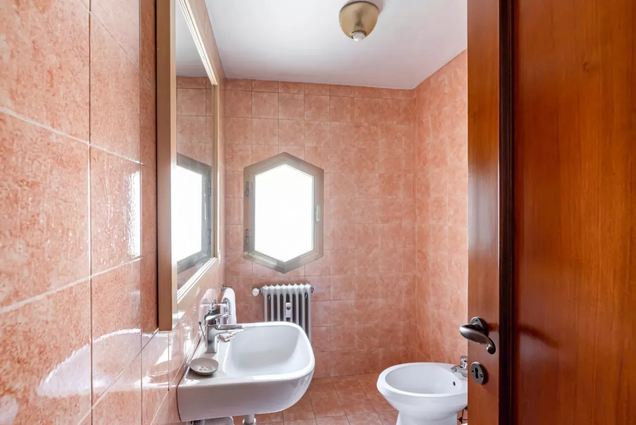 Un baño alicatado con lavabo, inodoro y ventanas.