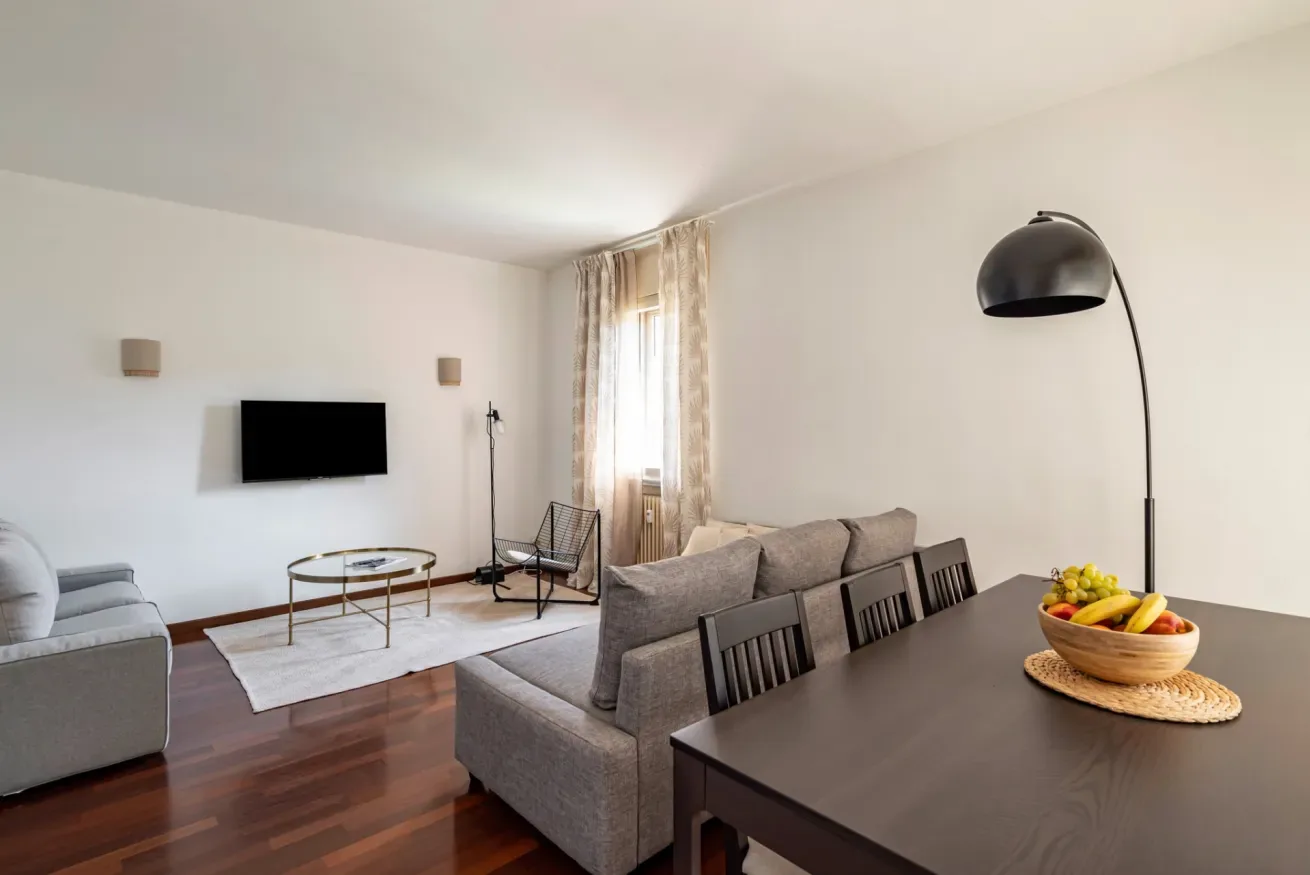 Una sala luminosa con asientos, un televisor y una mesa de comedor.