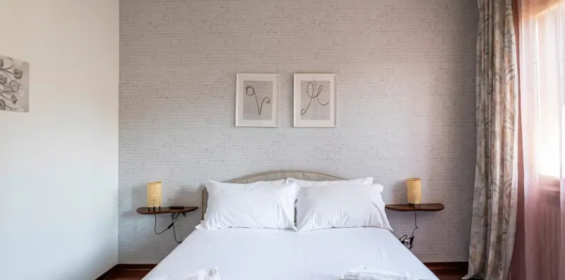 Un dormitorio con una cama, mesitas de noche y cuadros en la pared.