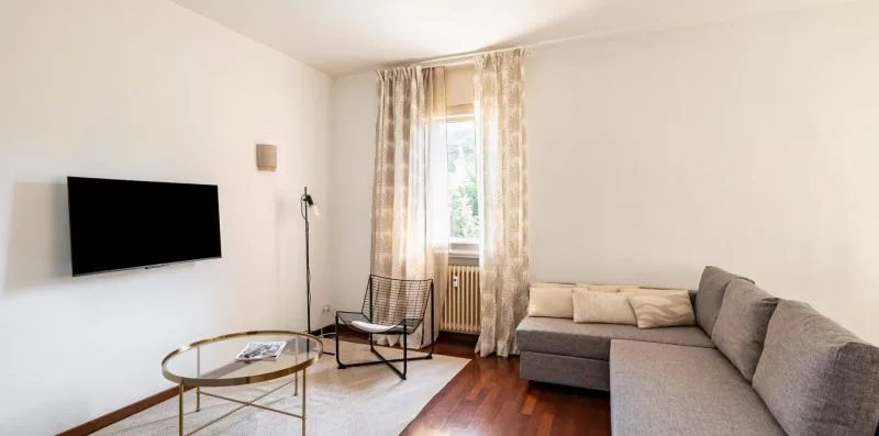 Una sala de estar con un sofá seccional, un televisor y una ventana con cortinas.