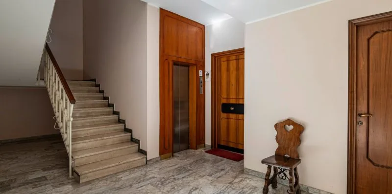 Un recibidor interior con una escalera y varias puertas de madera.