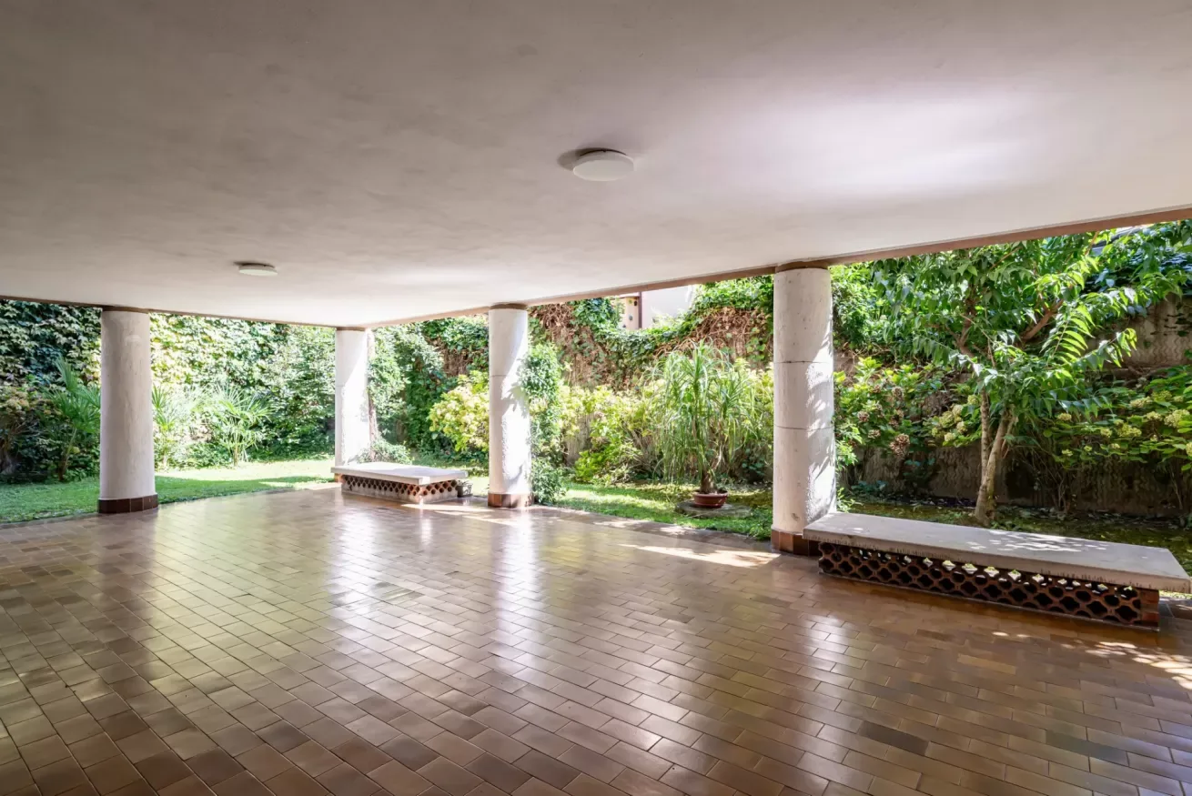 Un patio exterior cubierto con suelo de baldosas y vistas al jardín.