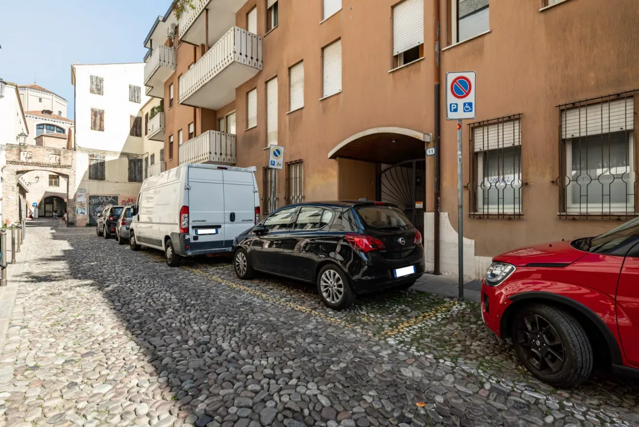 Una calle empedrada bordeada de coches estacionados y edificios de apartamentos.