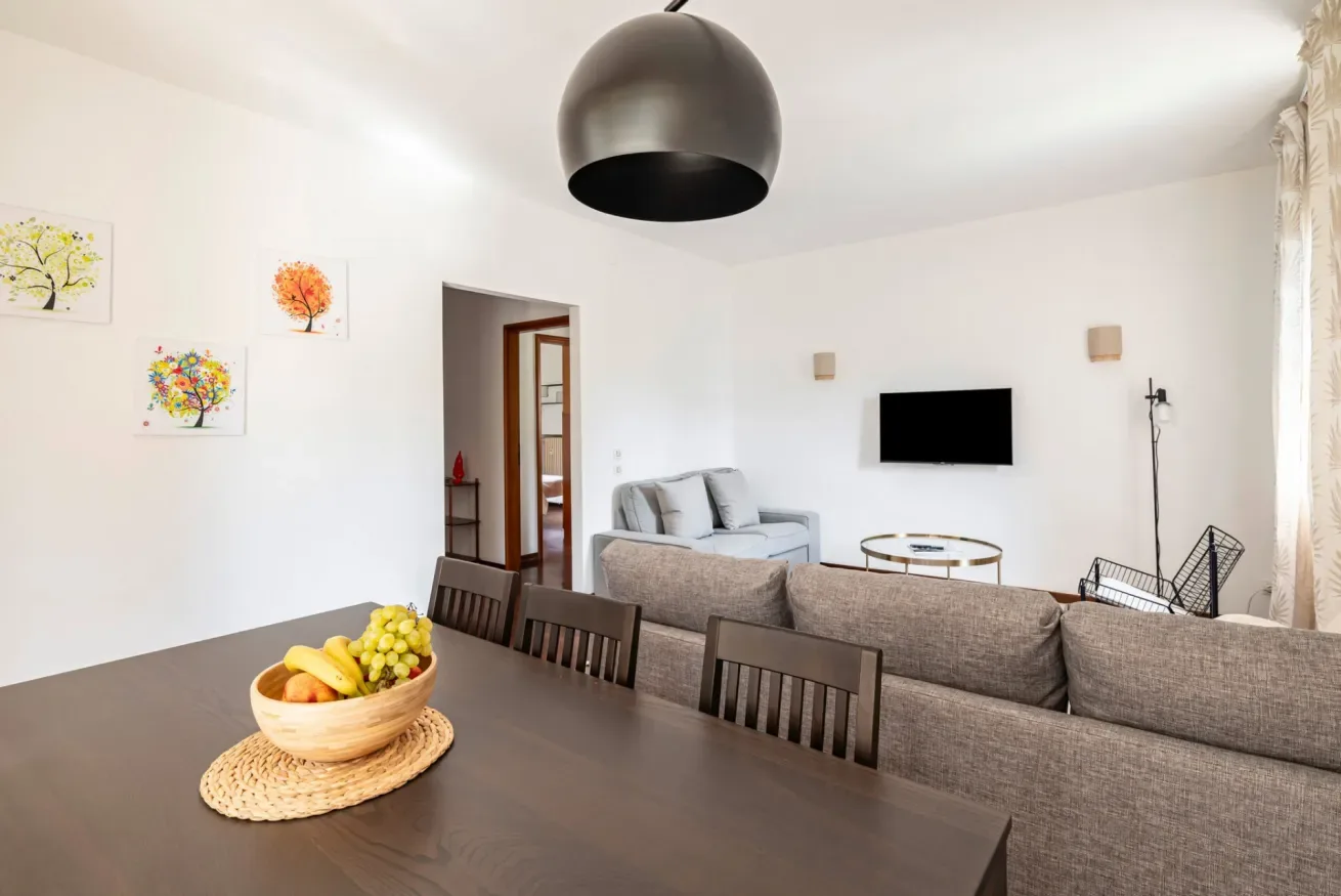 Una sala luminosa con asientos, un televisor y una mesa de comedor.