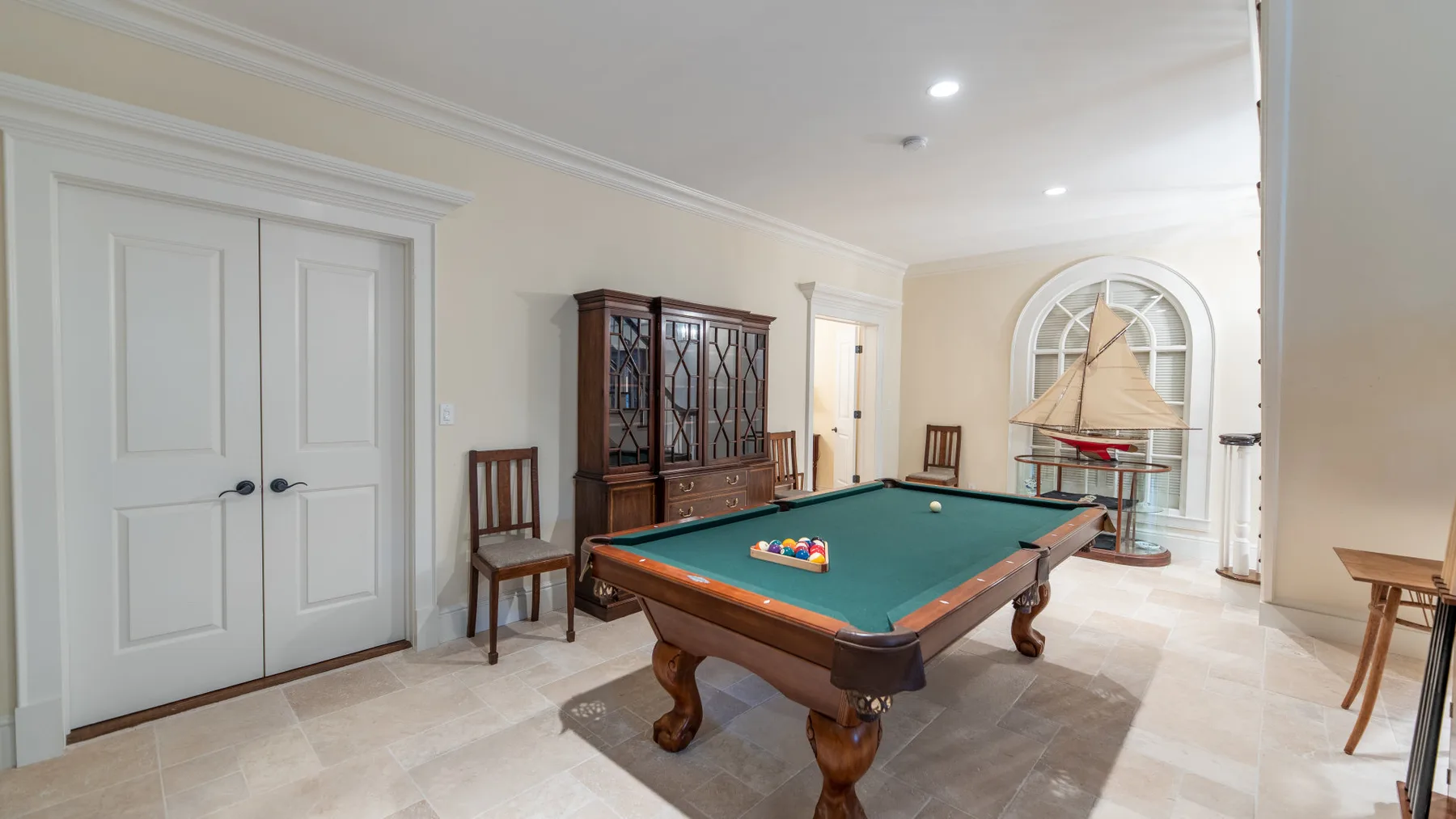 Una sala de juegos cuenta con una mesa de billar y una gran ventana arqueada.