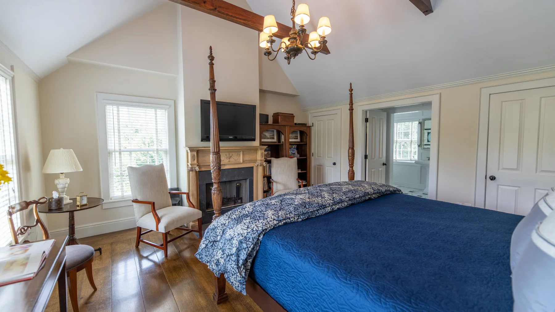 Un dormitorio con una cama grande, una chimenea y ventanas.