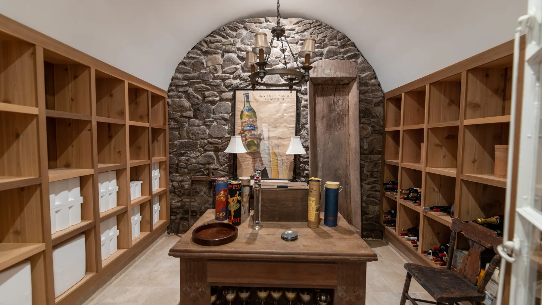 Sala de cata con estantes de madera y un nicho de piedra arqueado detrás de una mesa central.