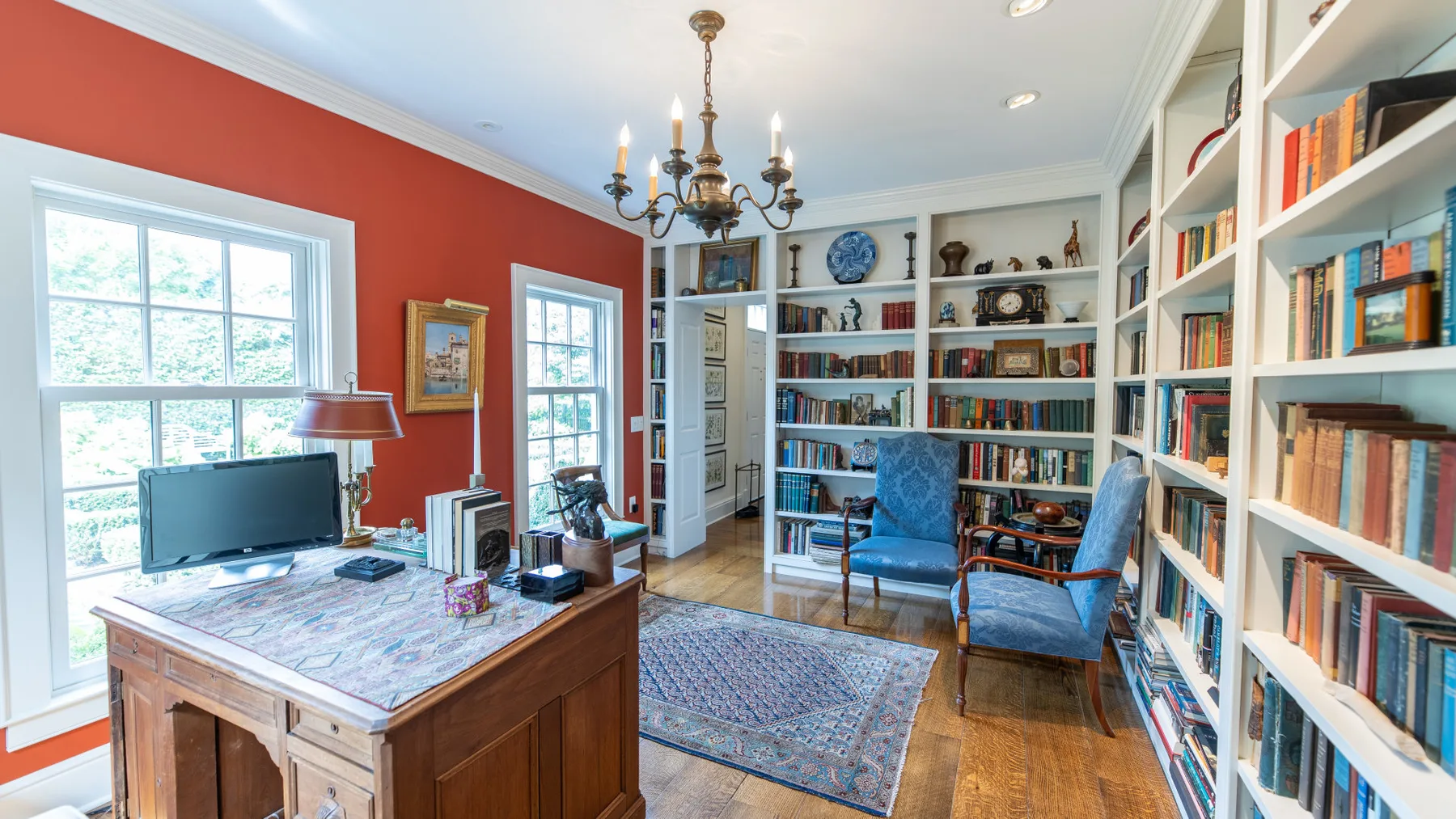 Una biblioteca en casa con estanterías altas, un escritorio de madera y asientos.