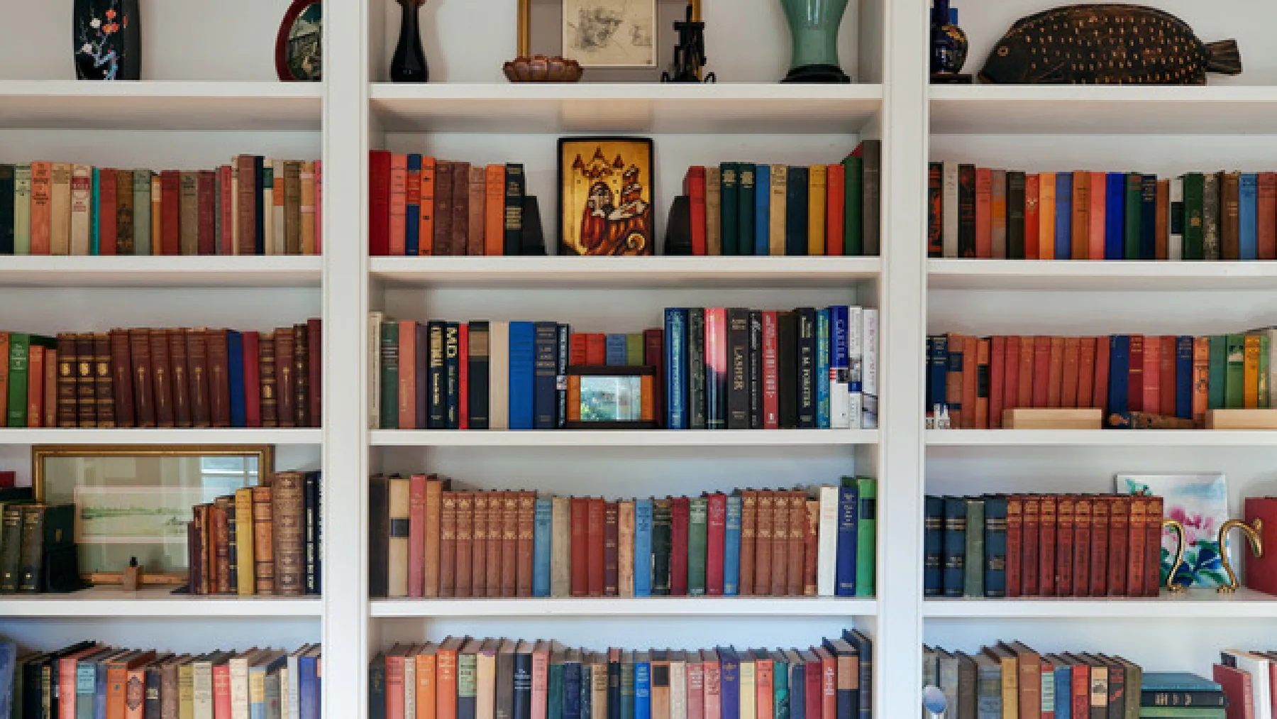 Una pared de estanterías muestra filas de libros y objetos decorativos.