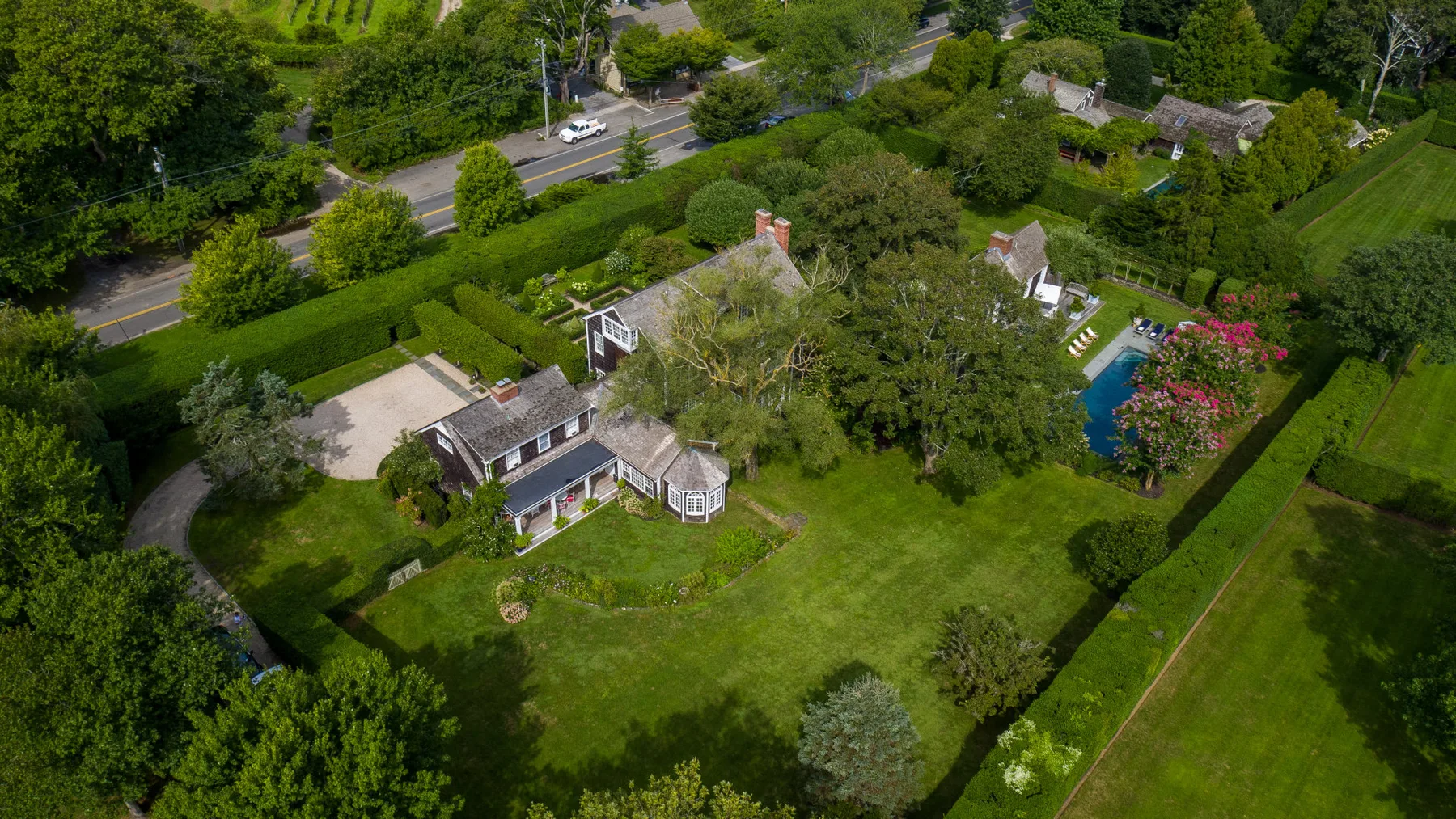 Vista aérea de una casa y sus jardines junto a una carretera.