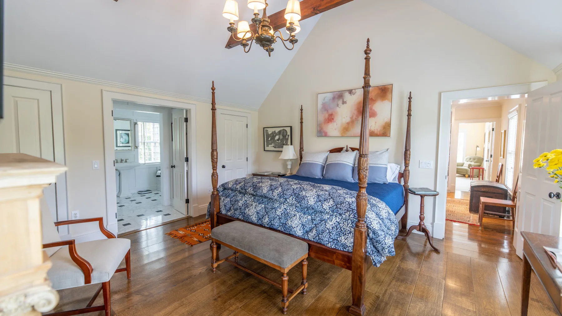 Un dormitorio con una cama con dosel, una mesa pequeña y suelo de madera.