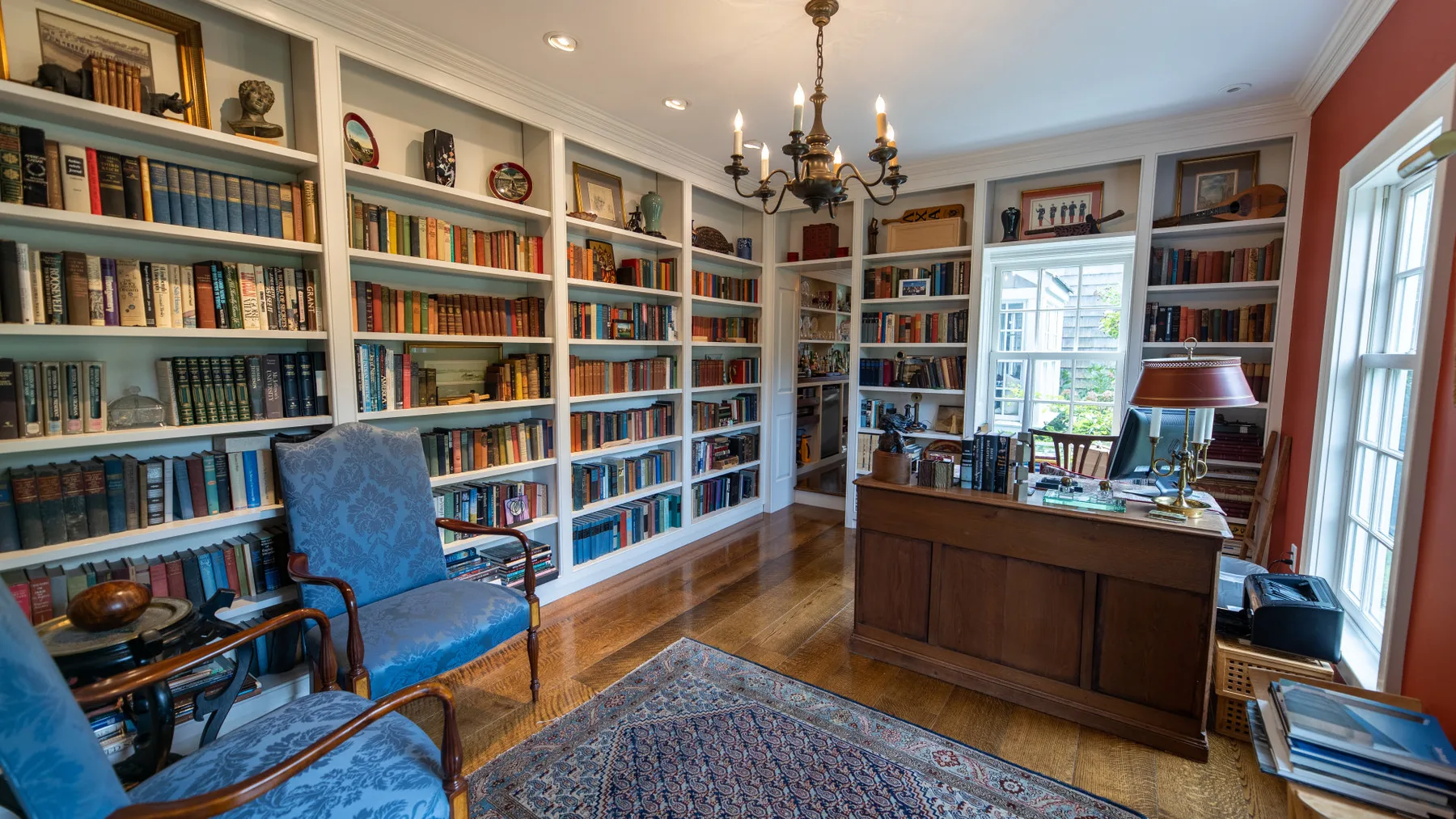 Una biblioteca con estanterías altas llenas de libros y un escritorio.