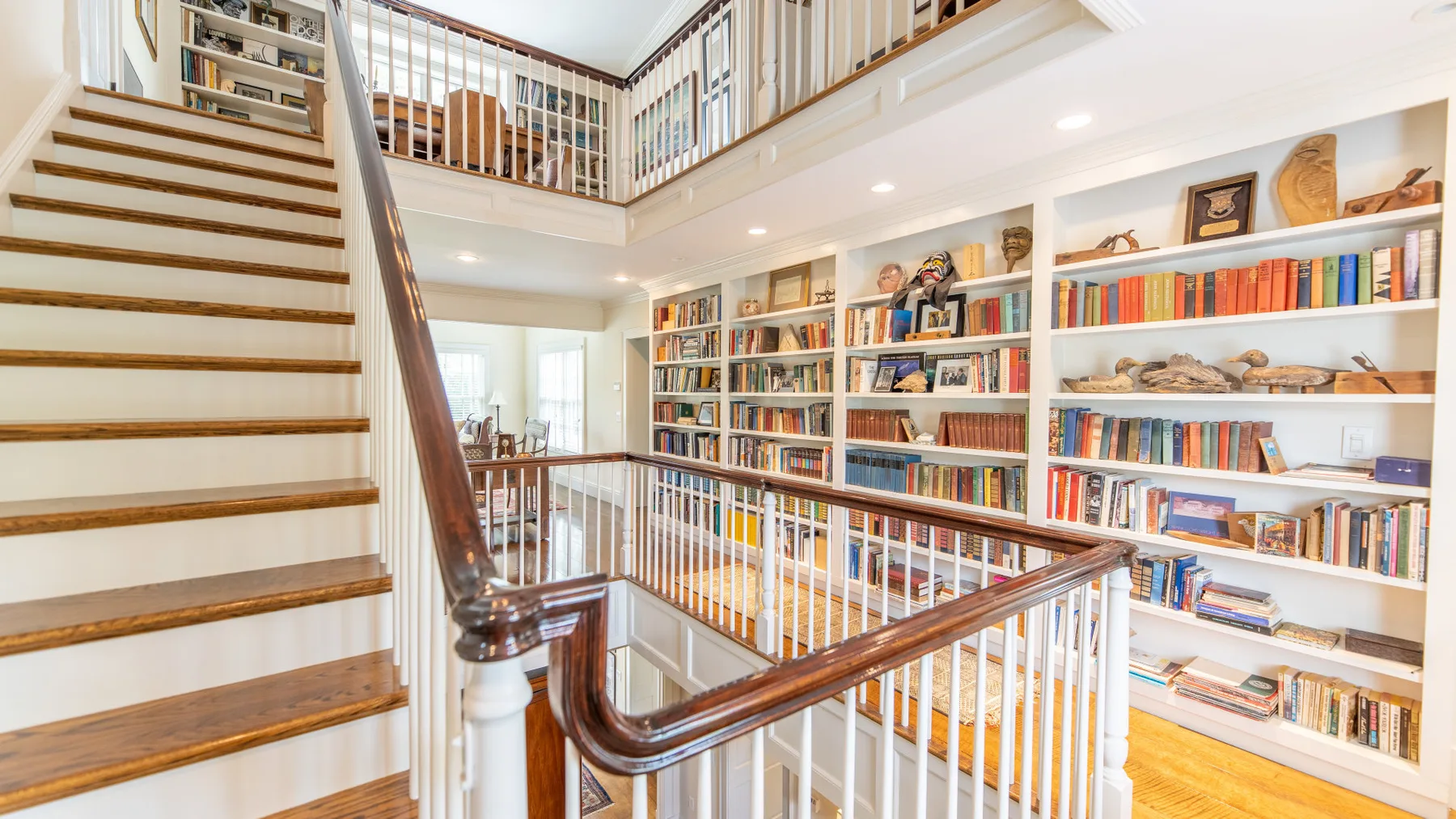Una biblioteca luminosa de varios niveles con estanterías y una escalera.