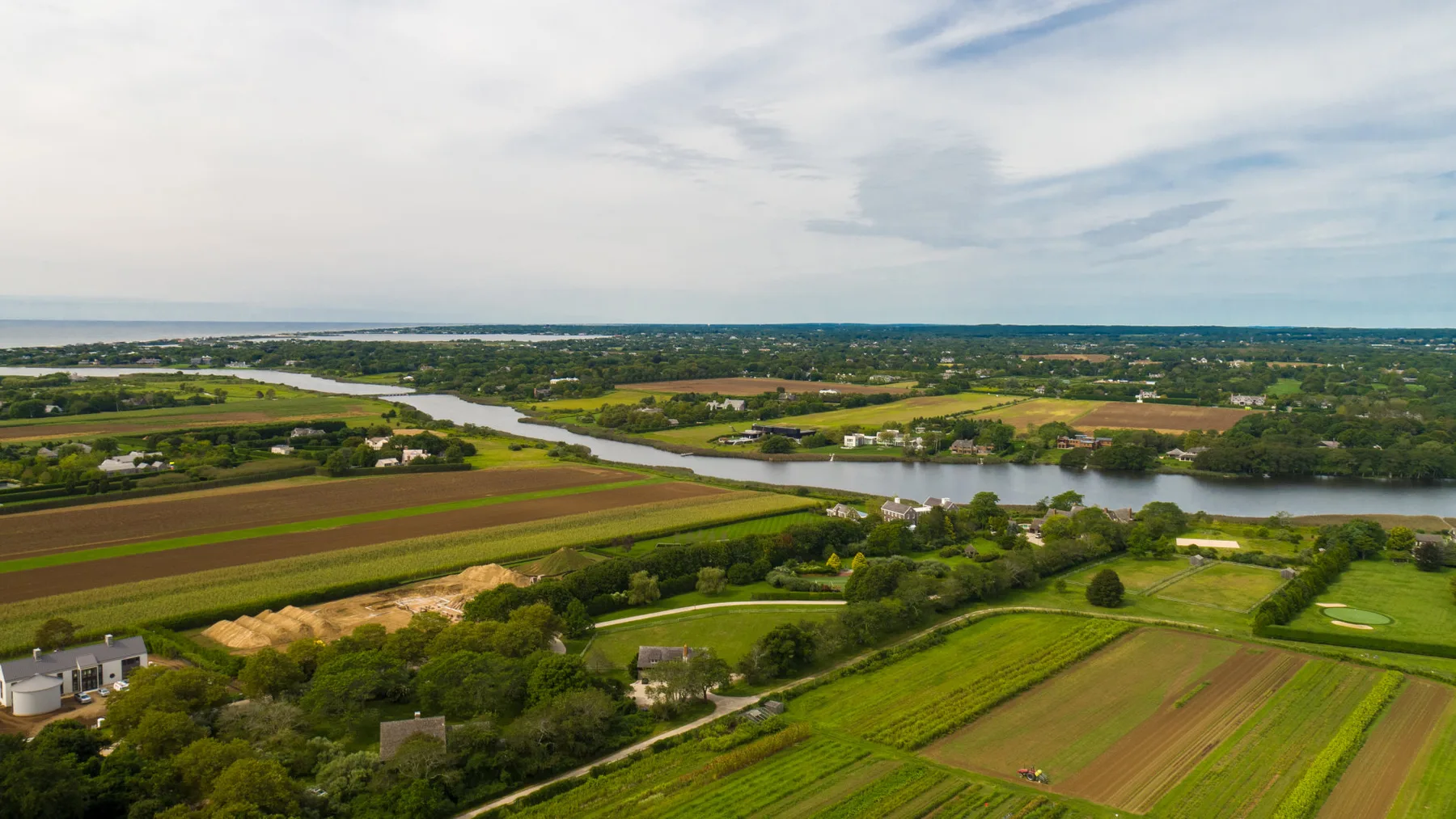 Vista aérea de campos cultivados y un río serpenteante bajo un cielo nublado.