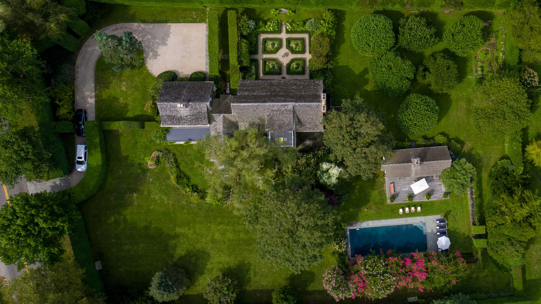 Vista aérea de una propiedad ajardinada con una casa grande y una piscina.