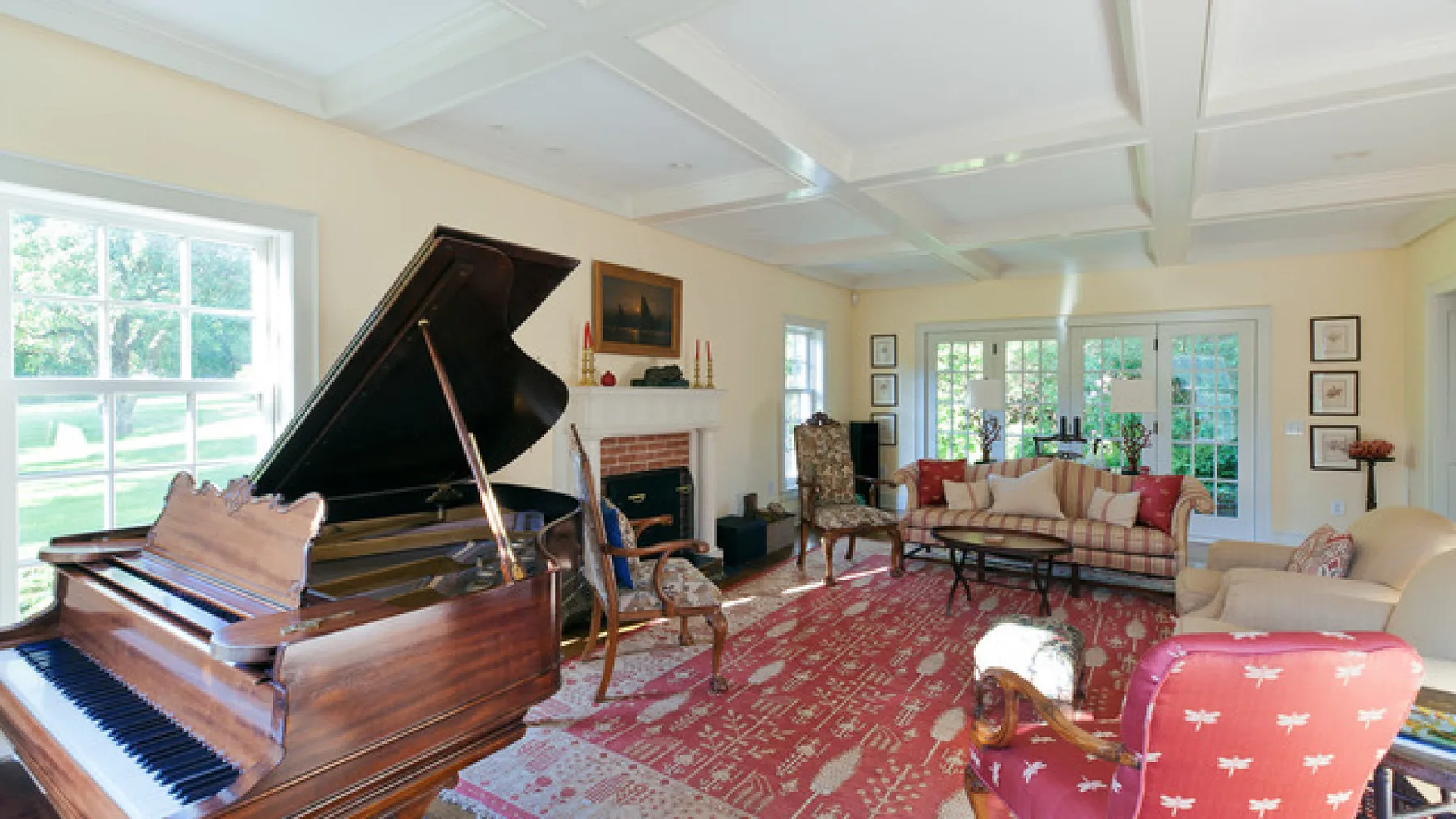 Una luminosa sala de estar con un piano de cola, asientos y una alfombra estampada.