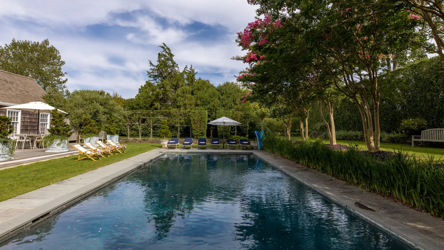 Una piscina al aire libre rodeada de árboles y asientos de descanso.