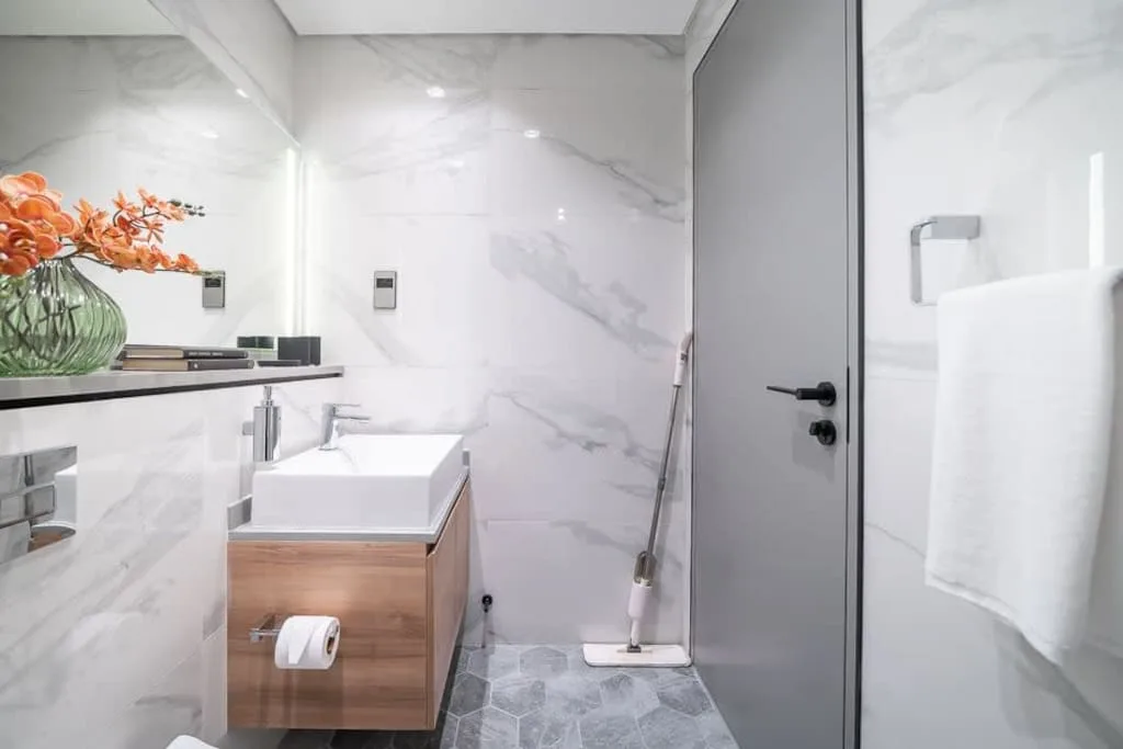 Un baño con lavabo y una puerta gris.