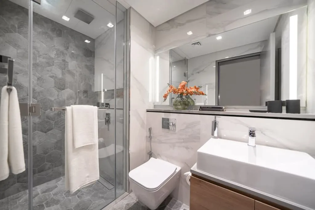 Baño moderno con ducha de vidrio, inodoro y lavabo.