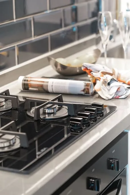 Una placa de cocina está sobre una encimera junto a un cuenco y un paño doblado.