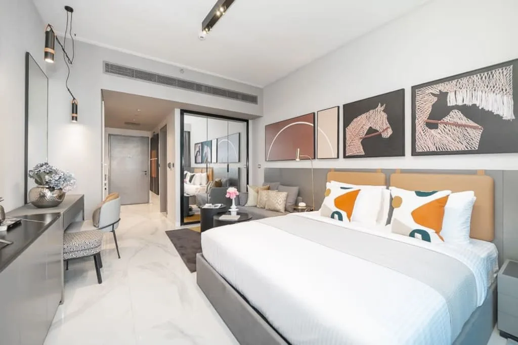 Un dormitorio luminoso con una cama bien tendida y cuadros sobre el cabecero.