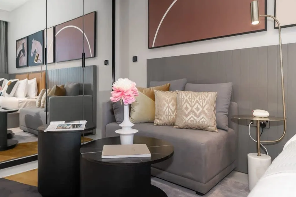 Una sala de estar moderna con un sofá gris, cojines decorativos y una mesa de centro redonda.