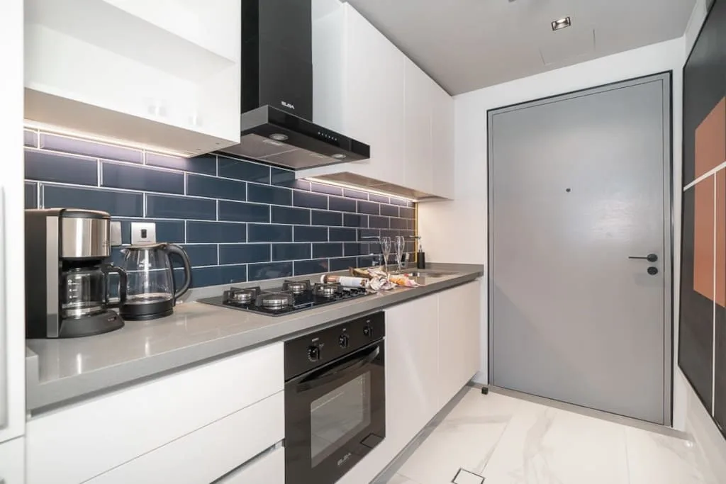Una cocina moderna con encimera, azulejos oscuros y horno integrado.