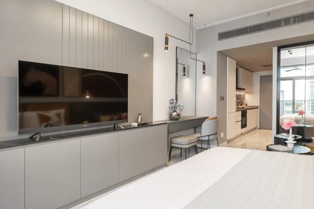 Un dormitorio moderno con un televisor en la pared y una pequeña zona de comedor.