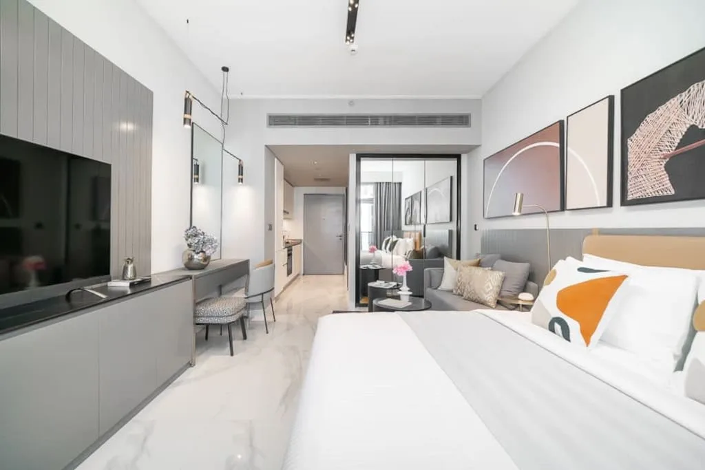 Un dormitorio moderno con una cama grande, una zona de estar y un televisor en la pared.
