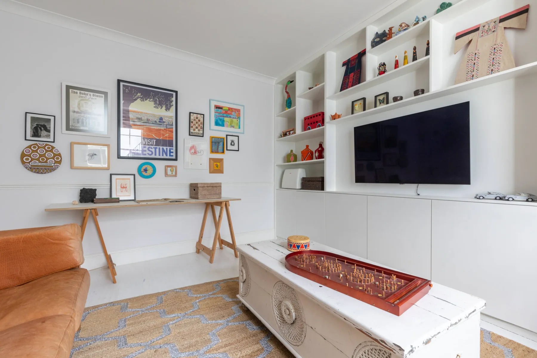 A living room with a television, wall shelves, and framed artwork.