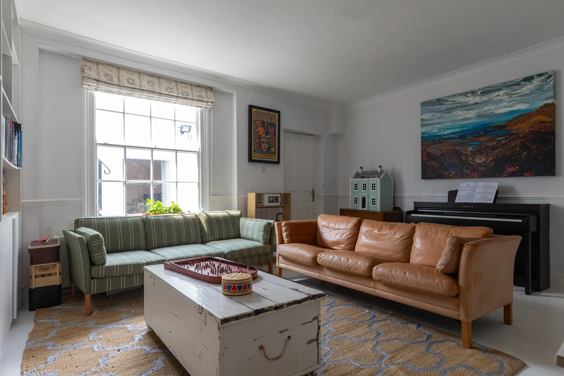 A living room with seating arranged around a coffee table and a piano.