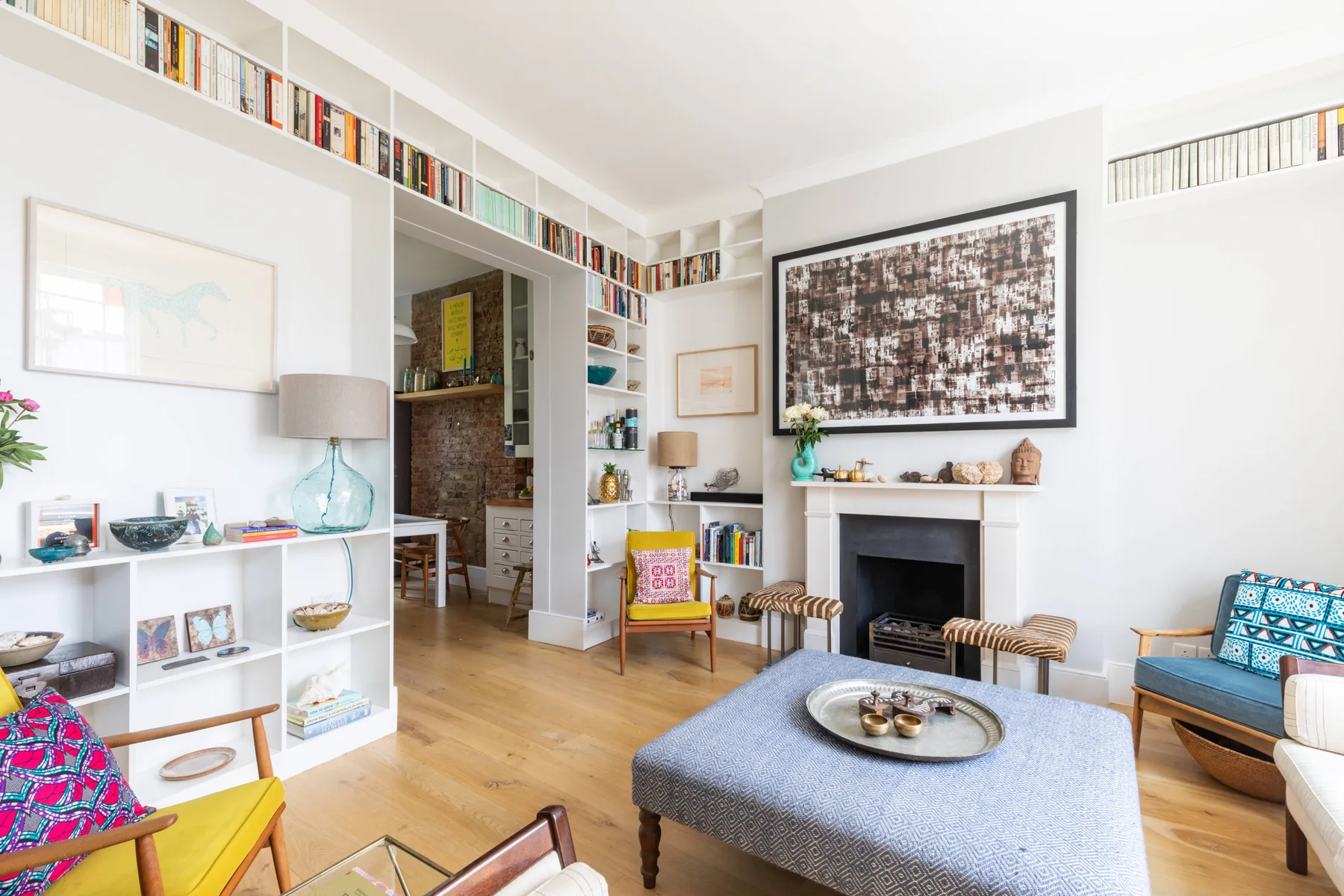 A bright living room with a fireplace, bookshelves, and seating.