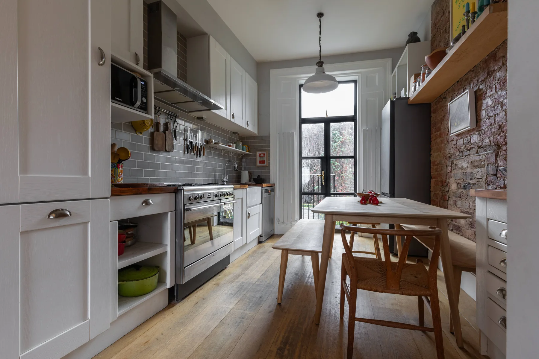 A kitchen and dining area with white cabinets and a wooden table.