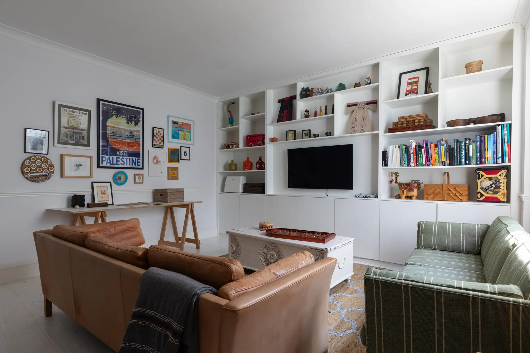 A living room with leather seating, built-in shelves, and a television.