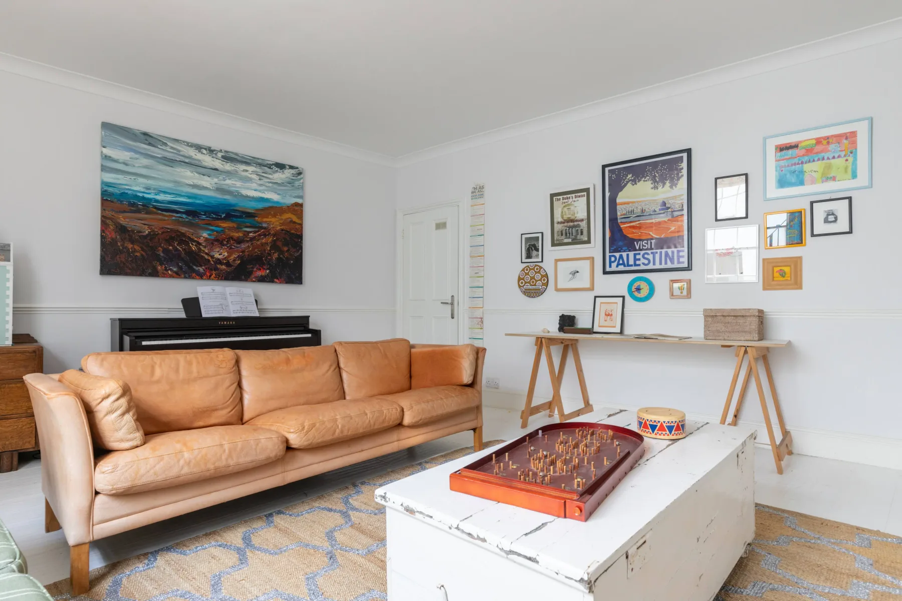 A living room with a tan sofa, framed artwork, and a low coffee table.