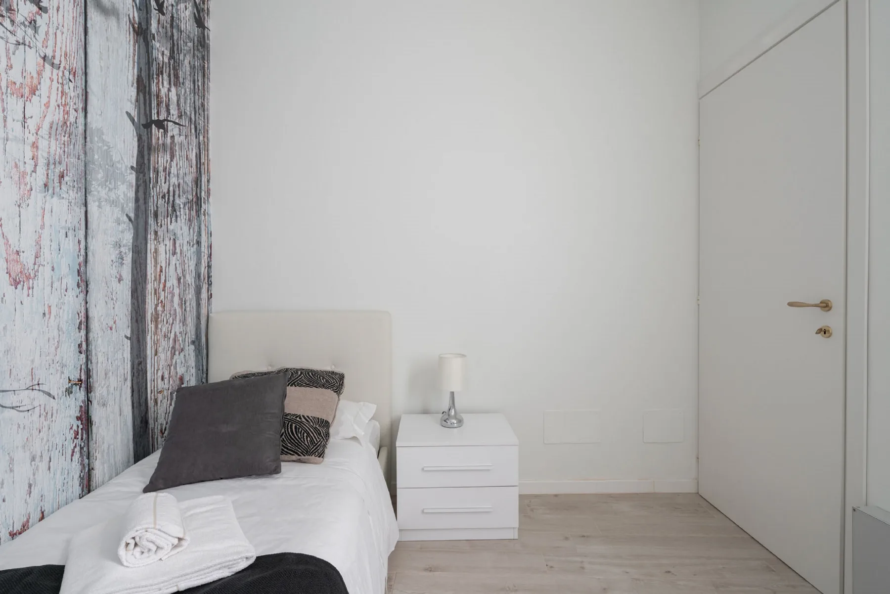 Un dormitorio con una cama junto a una pequeña mesita de noche.