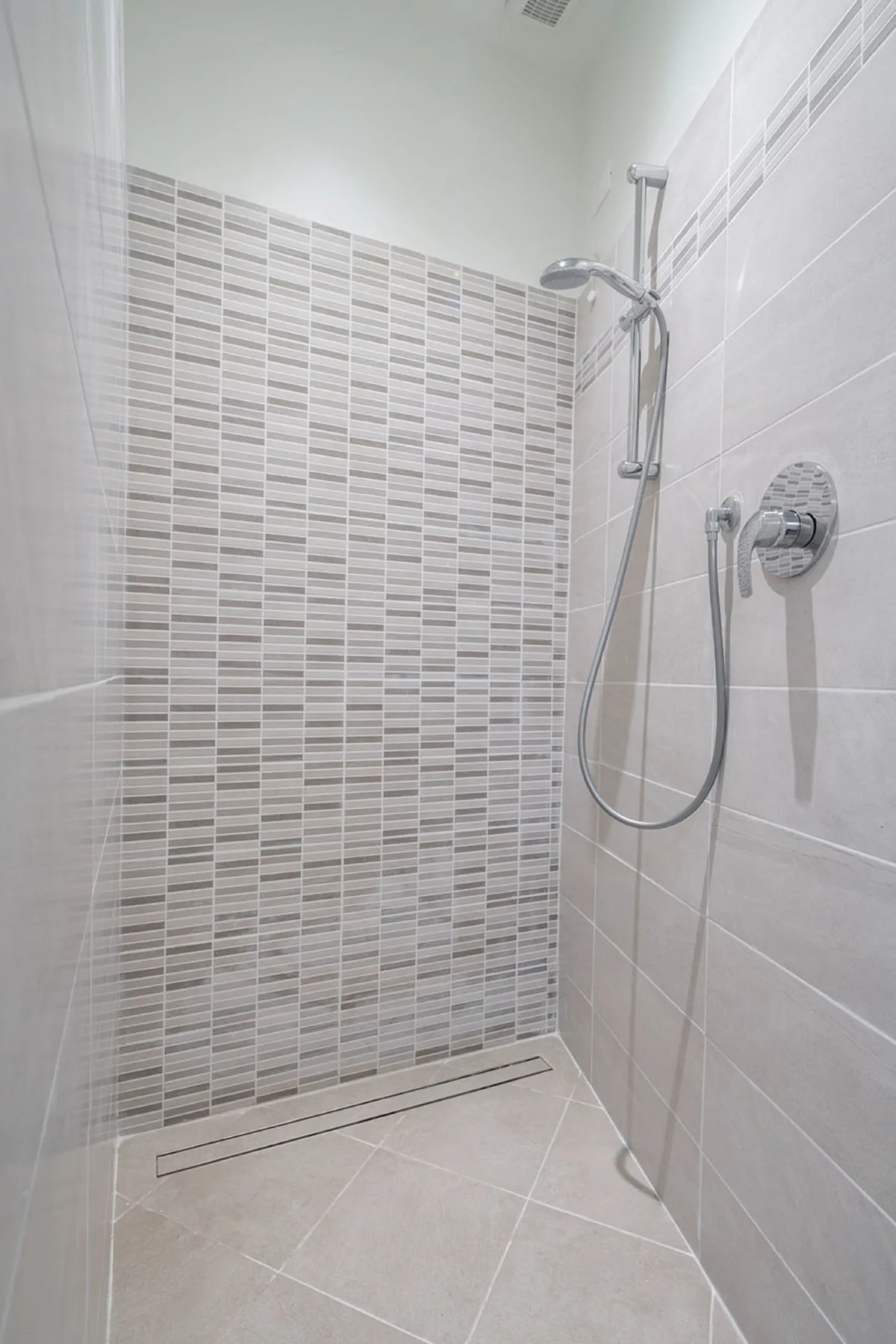 Una ducha revestida de azulejos con ducha de mano y controles en la pared.