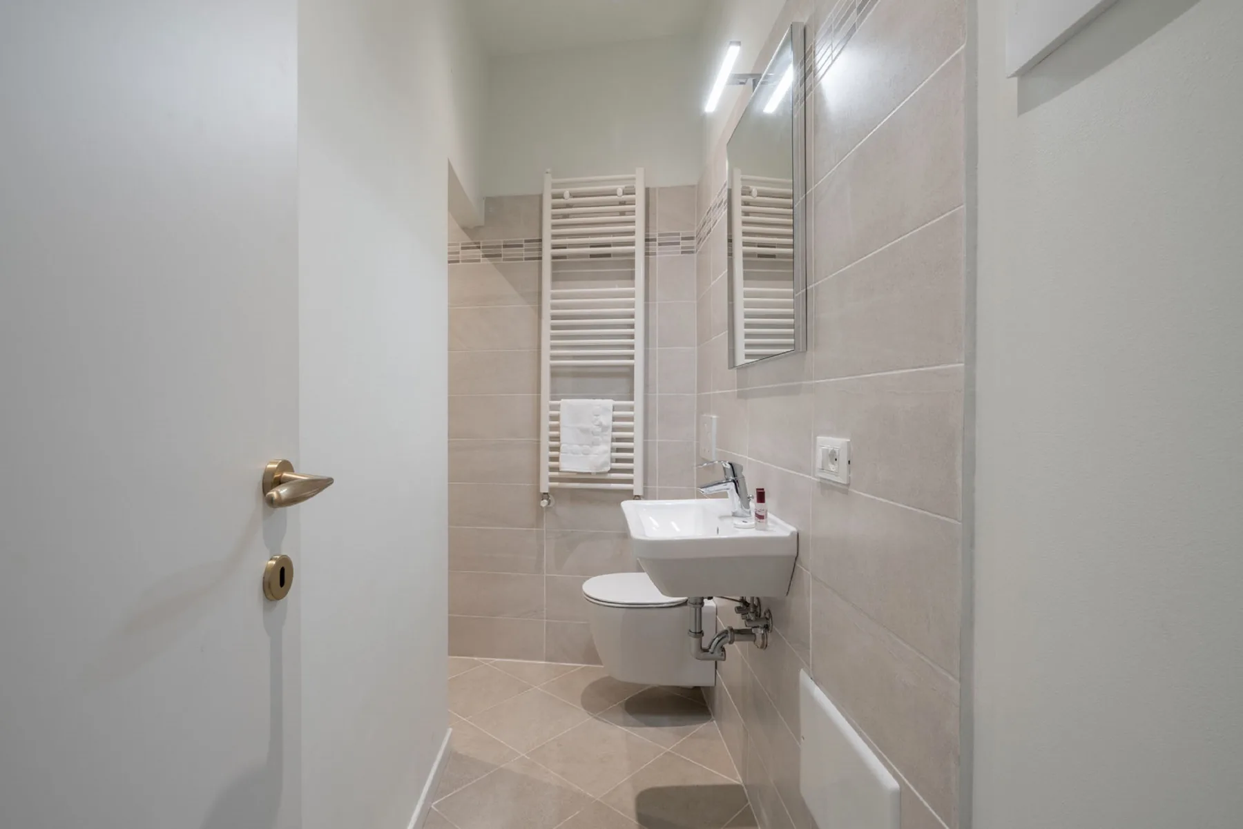 Un baño alicatado con lavabo e inodoro suspendidos.