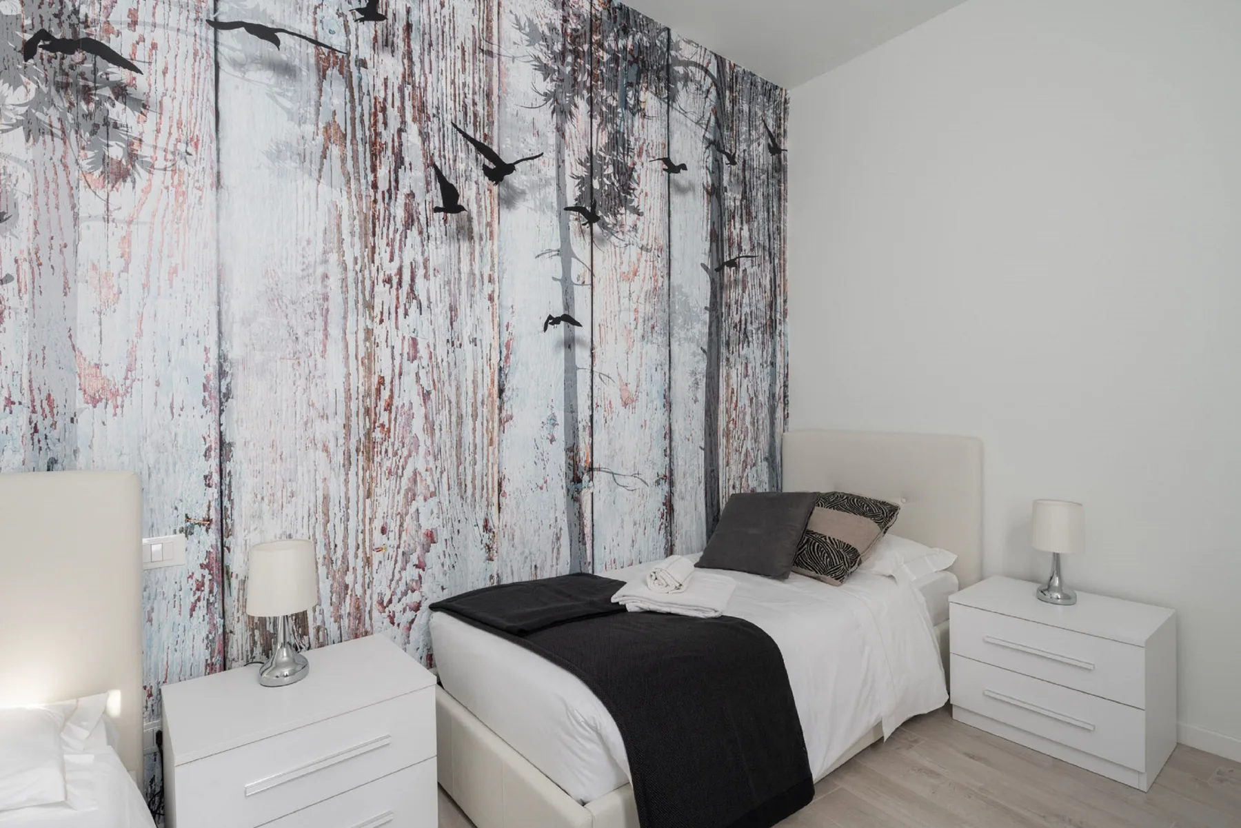 Un dormitorio con una cama tendida y una pared estampada detrás.