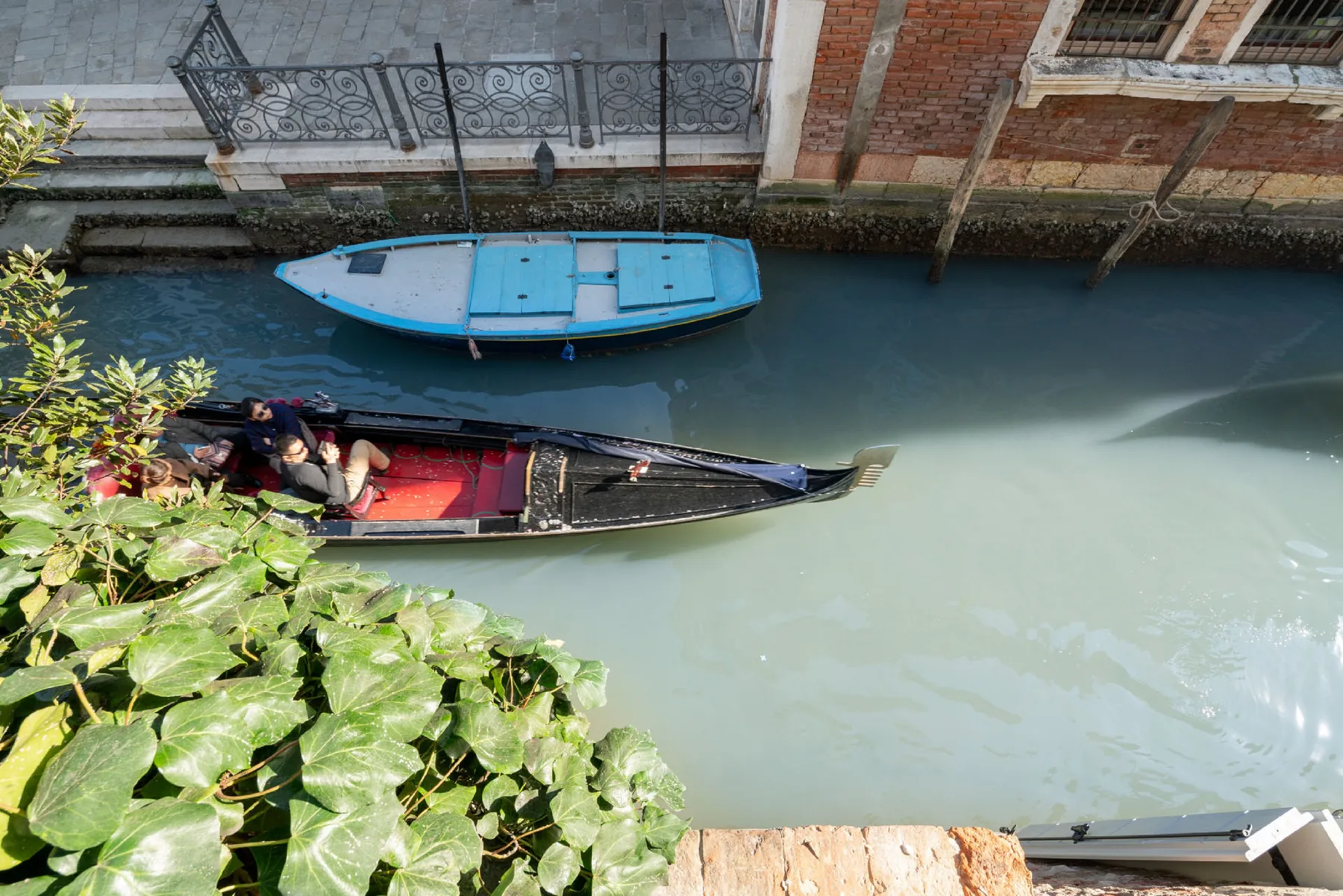 Un canal estrecho pasa junto a edificios antiguos de ladrillo y piedra, con barcos en el agua.