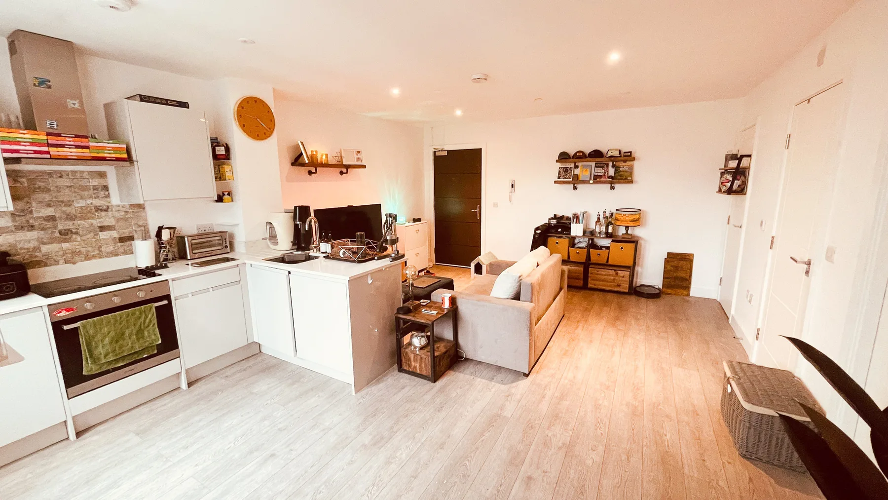 An open-plan kitchen and living area with light wood flooring.
